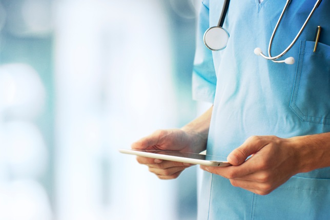 Person wearing medical scrubs holding tablet