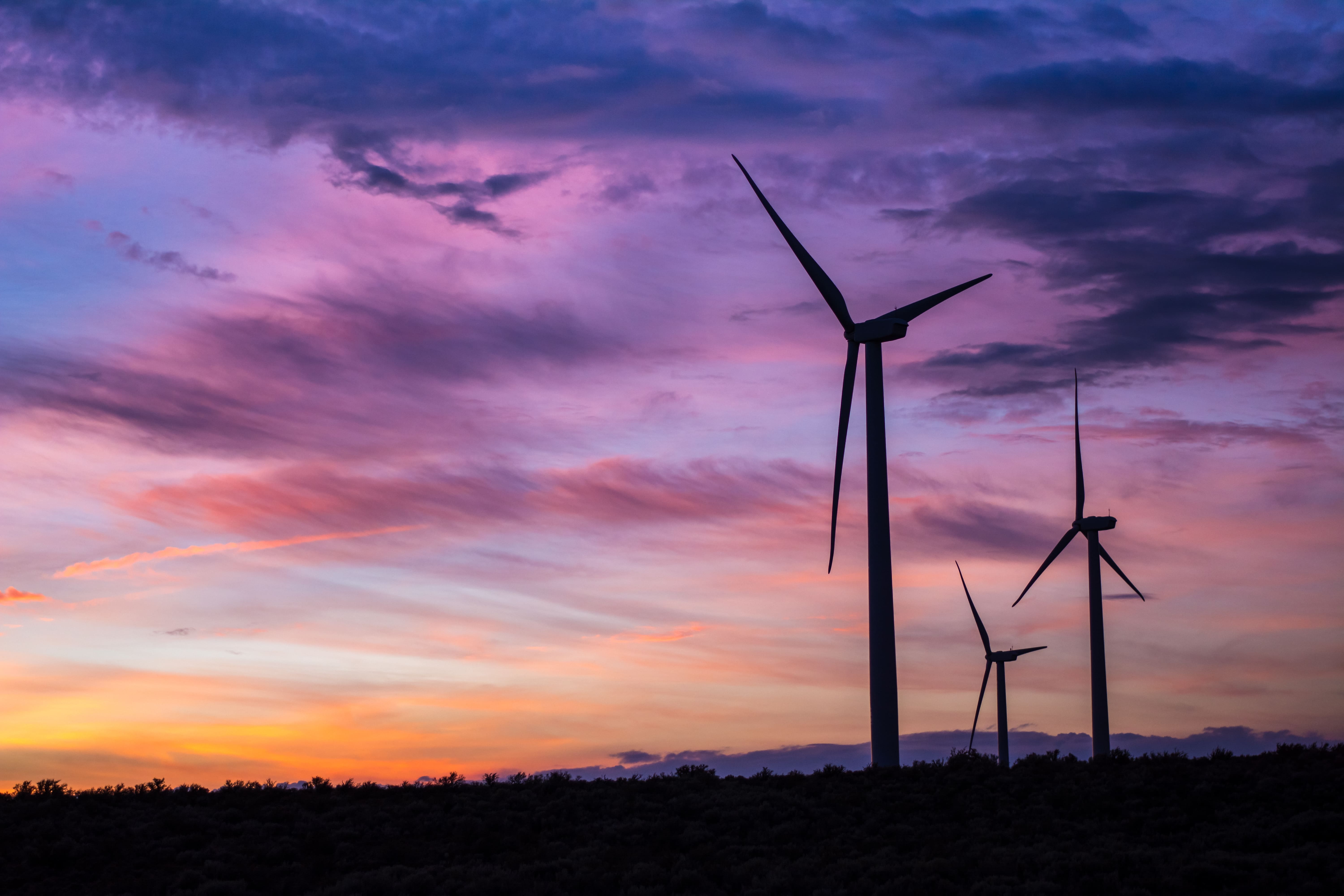 wind turbines in silhouette against a sunset