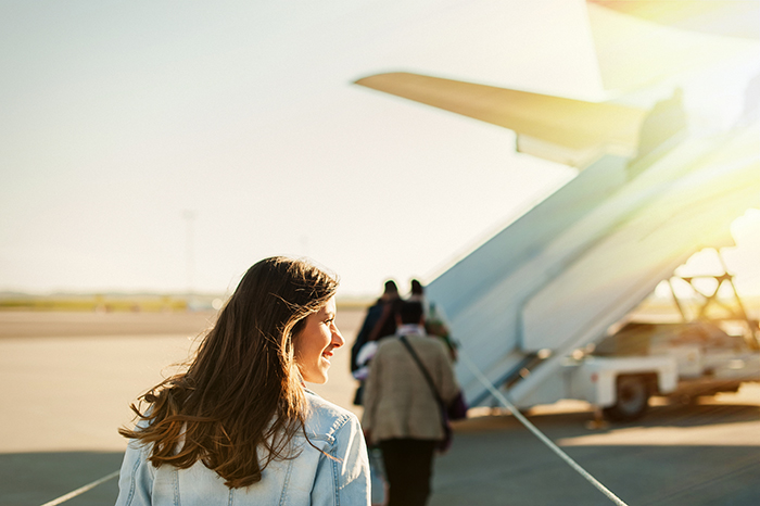 holiday woman boarding airplane with sun shining