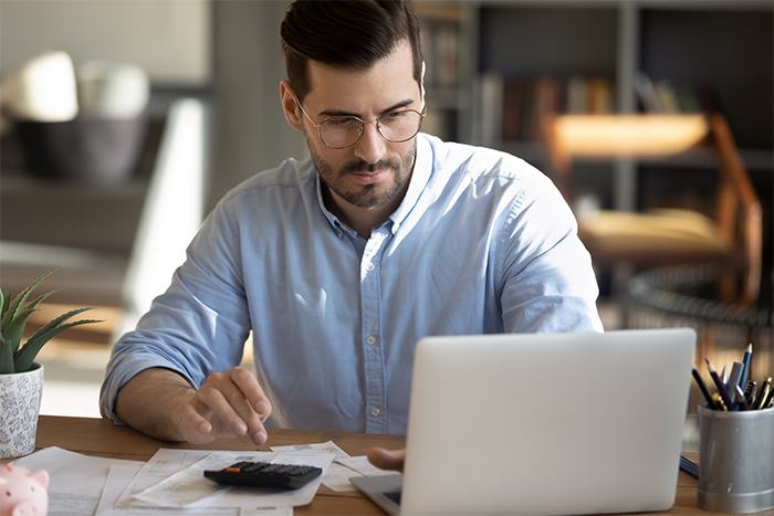 man_at_desk_with_calculator_and_laptop